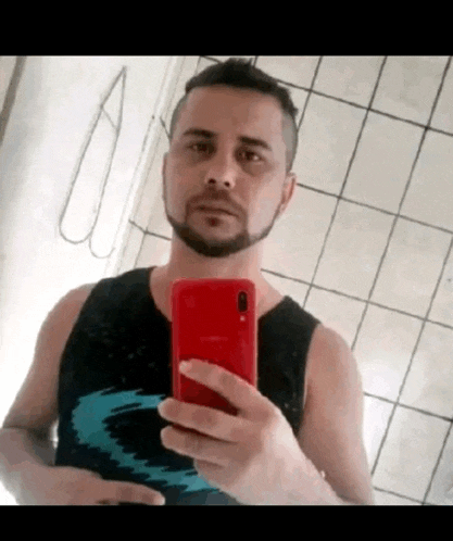 a man with a beard is taking a selfie with his phone .