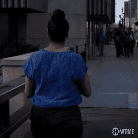 a woman in a blue shirt is walking down a sidewalk that says showtime on it