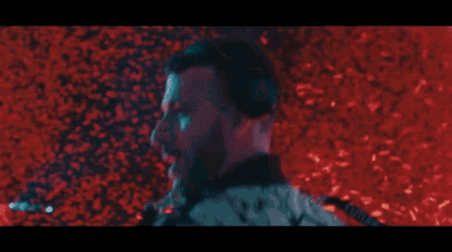 a man singing into a microphone in front of a fire