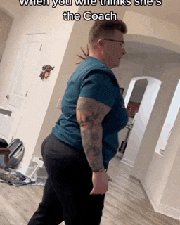 a man with tattoos on his arms is standing in a hallway in a living room .