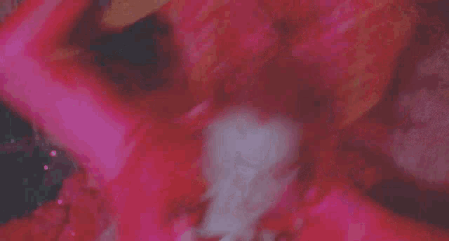 a woman with red hair and spikes on her arms is laying on a bed