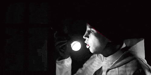 a man in a red hat and white jacket is holding a knife in his hand in a black and white photo .