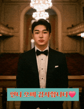 a man in a tuxedo stands in front of a sign that says ' i love you ' in korean