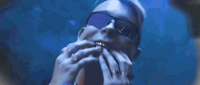 a man wearing sunglasses is eating a hamburger with his hands .