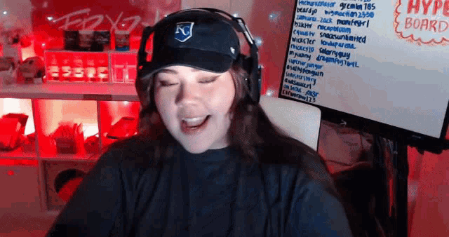 a woman wearing a hat and headphones is smiling in front of a white board that says hype board
