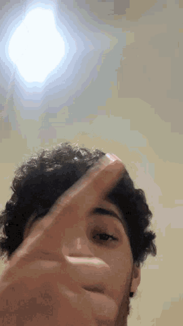 a man with curly hair is making a peace sign with his fingers .