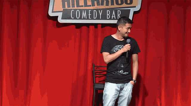 a man stands in front of a comedy bar