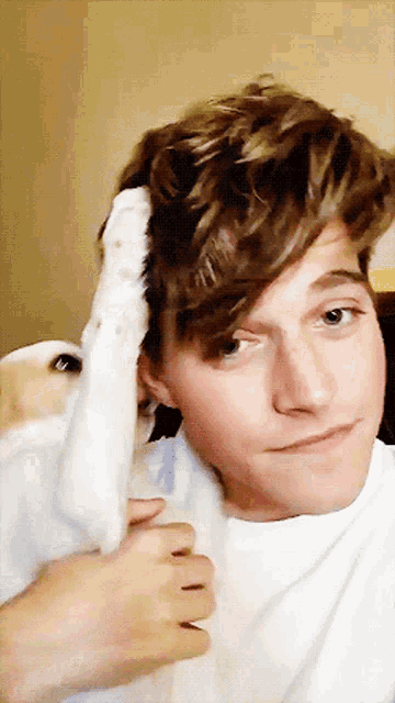 a young man is holding a dog 's paw in front of his head
