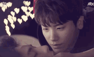 a man and a woman are laying on a bed with hearts hanging from the ceiling .