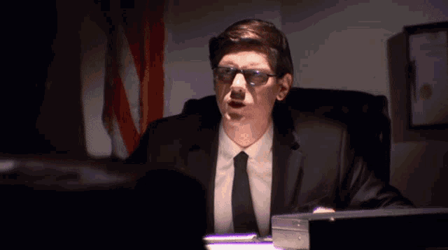 a man in a suit and tie sitting at a desk