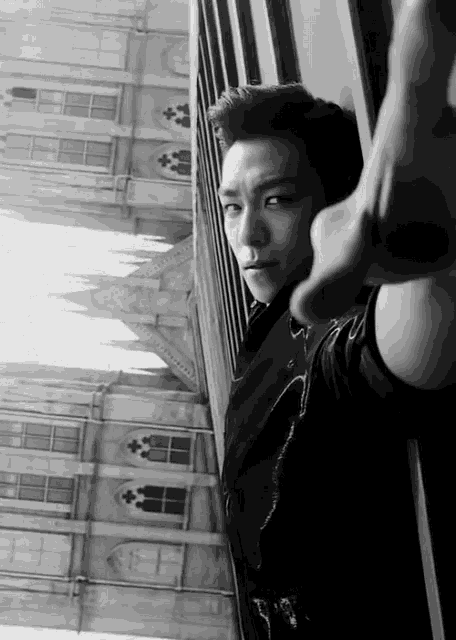 a black and white photo of a man looking out of a window