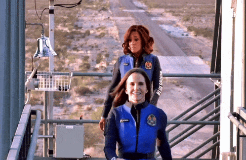 a woman wearing a blue vest with the word blue origin on it