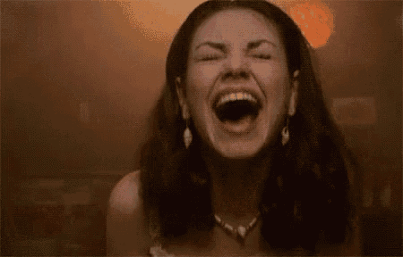 a close up of a woman laughing with her mouth open .