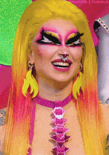 a close up of a drag queen 's face with a pink necklace and earrings