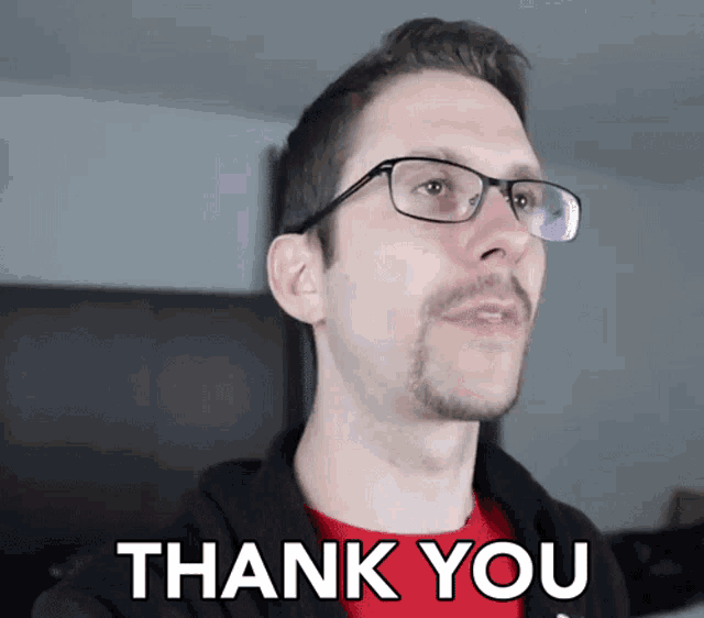 a man wearing glasses and a red shirt with the words thank you below him