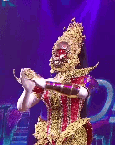 a woman in a gold and red costume with a mask on