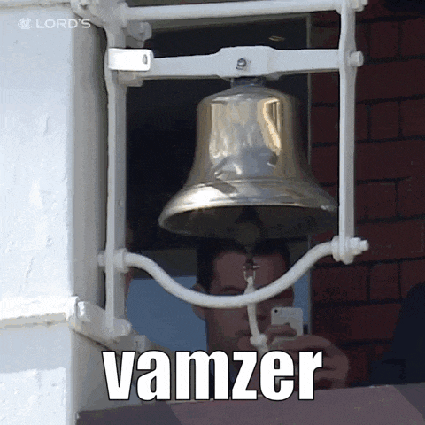a man taking a picture of a bell with the word vamzer on the bottom