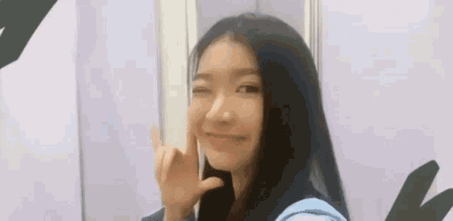 a woman with long black hair is making a peace sign with her finger .