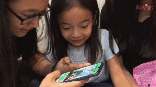 a little girl is playing a game on a cell phone with the words " zorocute " on the bottom