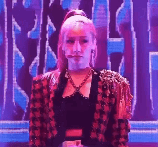 a woman with pink hair is standing in front of a purple screen .