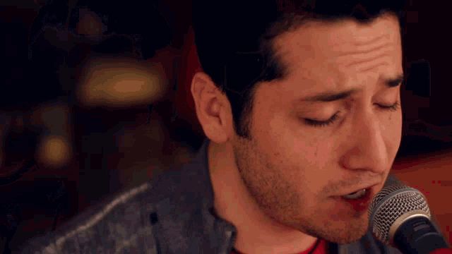 a man is singing into a shure microphone with his eyes closed
