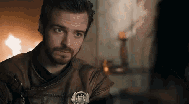 a man with a beard is wearing a brown leather jacket with a badge on it that says ' a ' on it