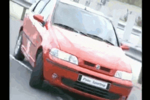 a red fiat palio sporting is driving down a road