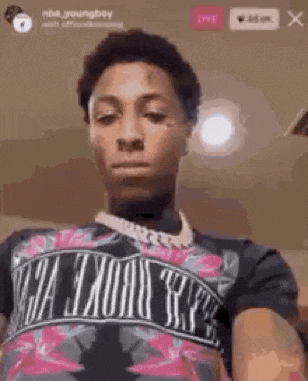 a young man is wearing a t-shirt and a necklace .