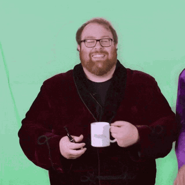 a man in a robe is holding a mug that says ' harry potter ' on it .