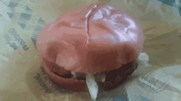a pink hamburger sits on a piece of chicken wrapped paper