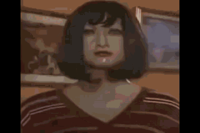 a woman wearing a wig and a striped shirt is standing in front of a painting .