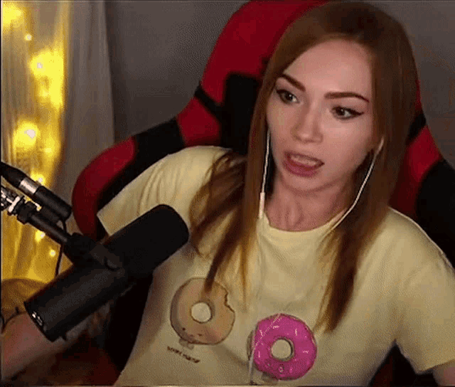 a woman wearing a yellow t-shirt with donuts on it is talking into a microphone .