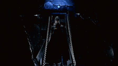 a man in a batman costume with a yellow bat symbol on his chest