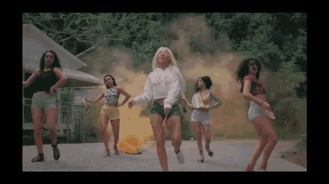 a group of young women are dancing in front of a smoke bomb