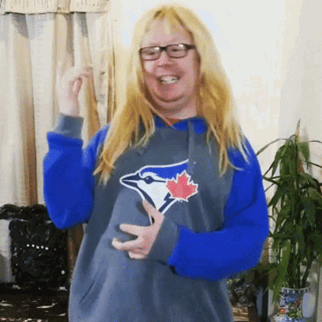 a woman is wearing a blue jays hoodie and glasses