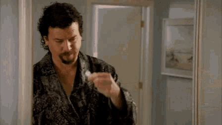 a man with curly hair and a beard is brushing his teeth