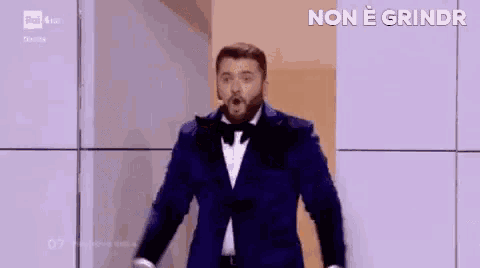 a man in a suit is standing in front of a screen that says non e grindr on it