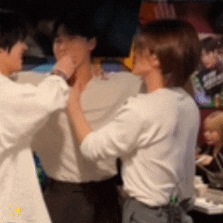 a group of people are standing next to each other and one of them is holding another person 's neck .
