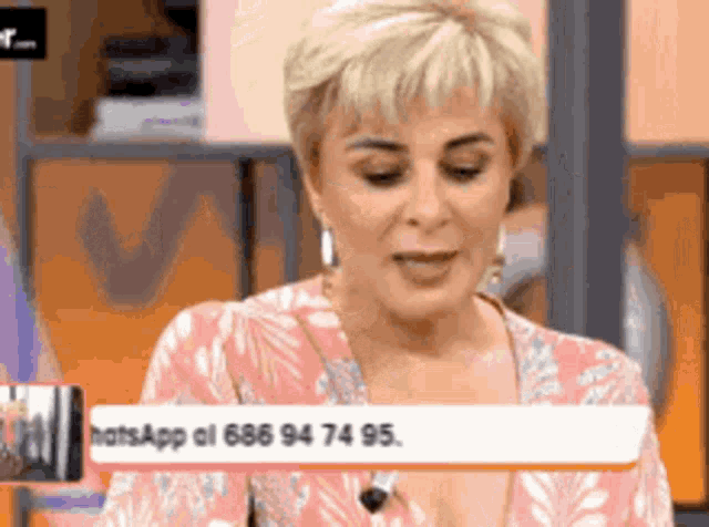 a woman in a pink floral shirt is talking on a phone