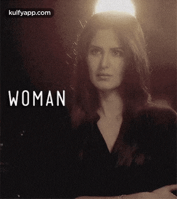 a woman is standing in front of a light with the word woman written on the bottom .