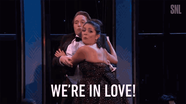 a man and a woman are dancing on a stage with the words we 're in love behind them