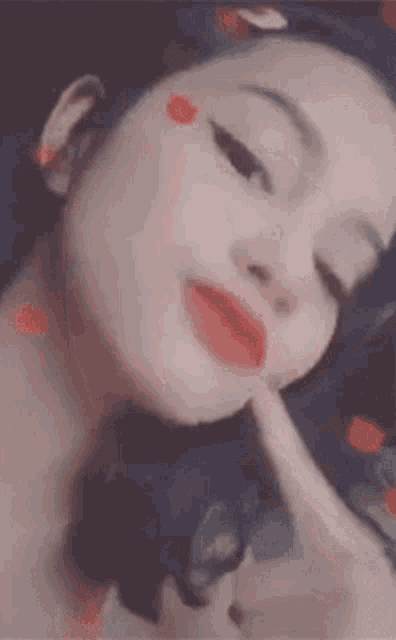 a close up of a woman 's face with red lipstick and hearts on it .