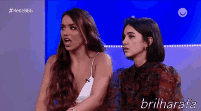 two women are sitting next to each other with the words brilharafa on the bottom right