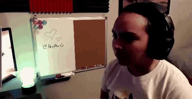 a man wearing headphones is sitting in front of a whiteboard with a heart drawn on it