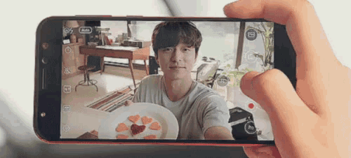 a person is taking a picture of a man holding a plate with hearts on it .