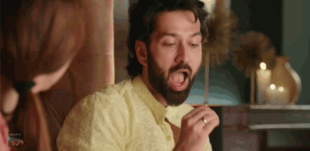 a man with a beard is sitting in a chair with his mouth open