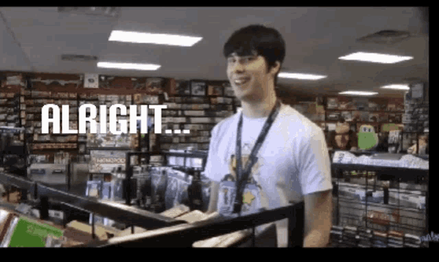 a man in a white shirt is standing in a store with the words " alright " on the screen