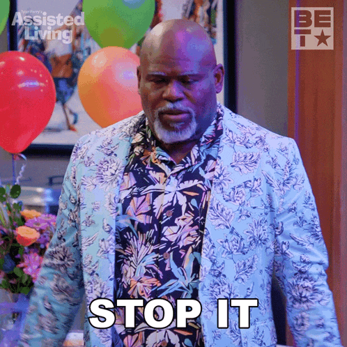 a man wearing a floral shirt and a blue jacket says " stop it "