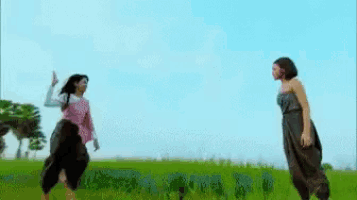 two women are standing next to each other in a field .