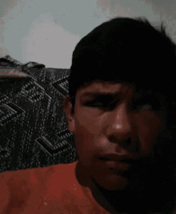 a close up of a young man 's face with a patterned blanket in the background